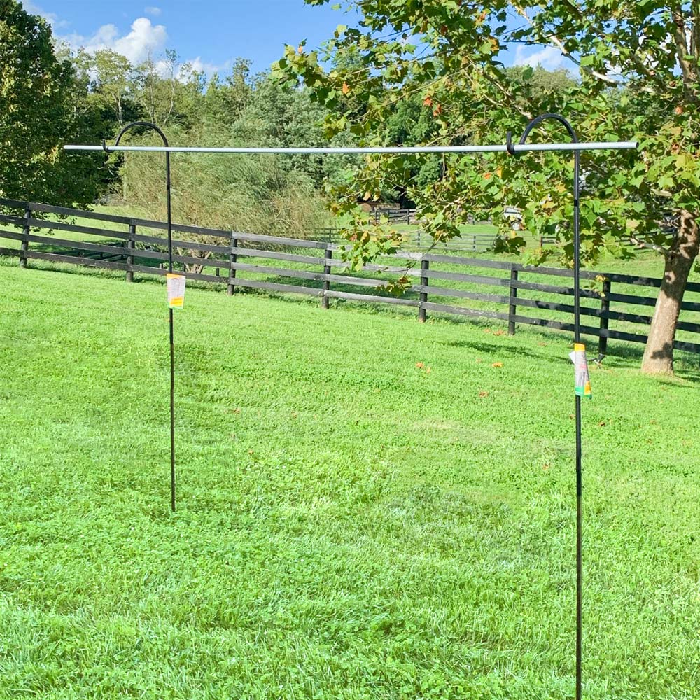 Tube placed on top of metal hooks posted in grass.