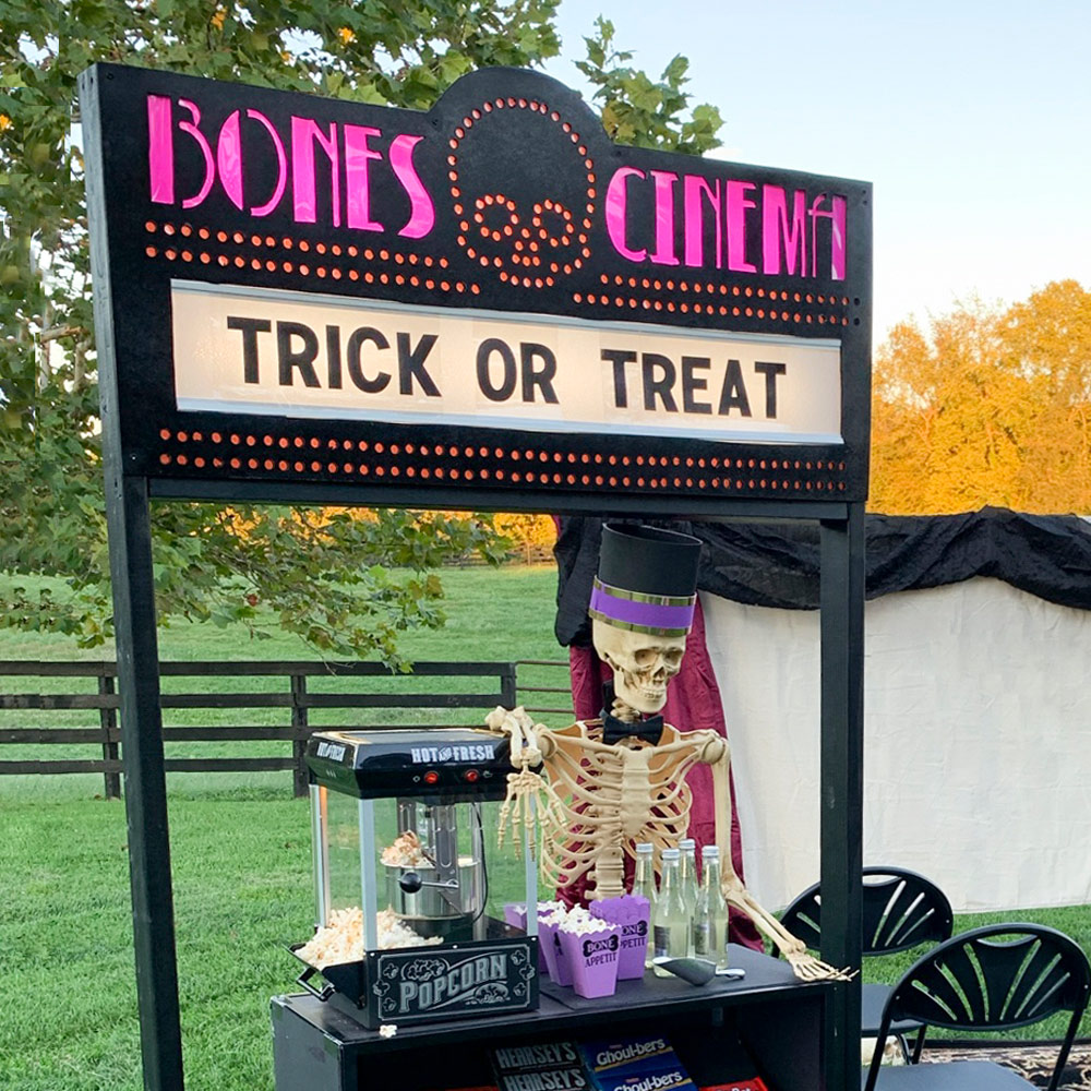Bones Cinema marquee sign with skeleton and popcorn machine stand
