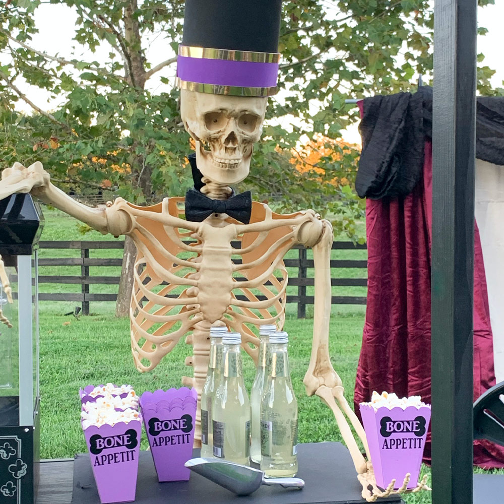 Skeleton at concession stand with popcorn and drinks.