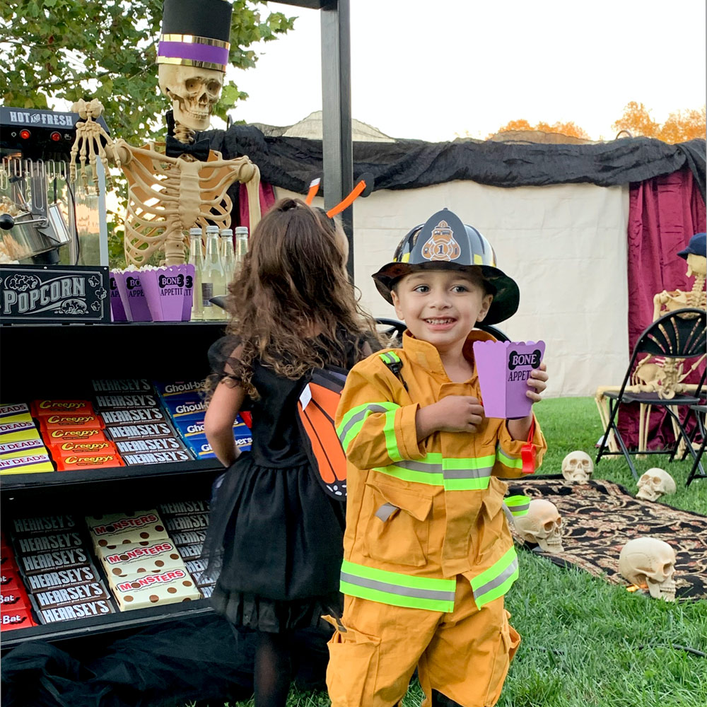 Little girl and Little boy in firefighter costume in front of concession stand.