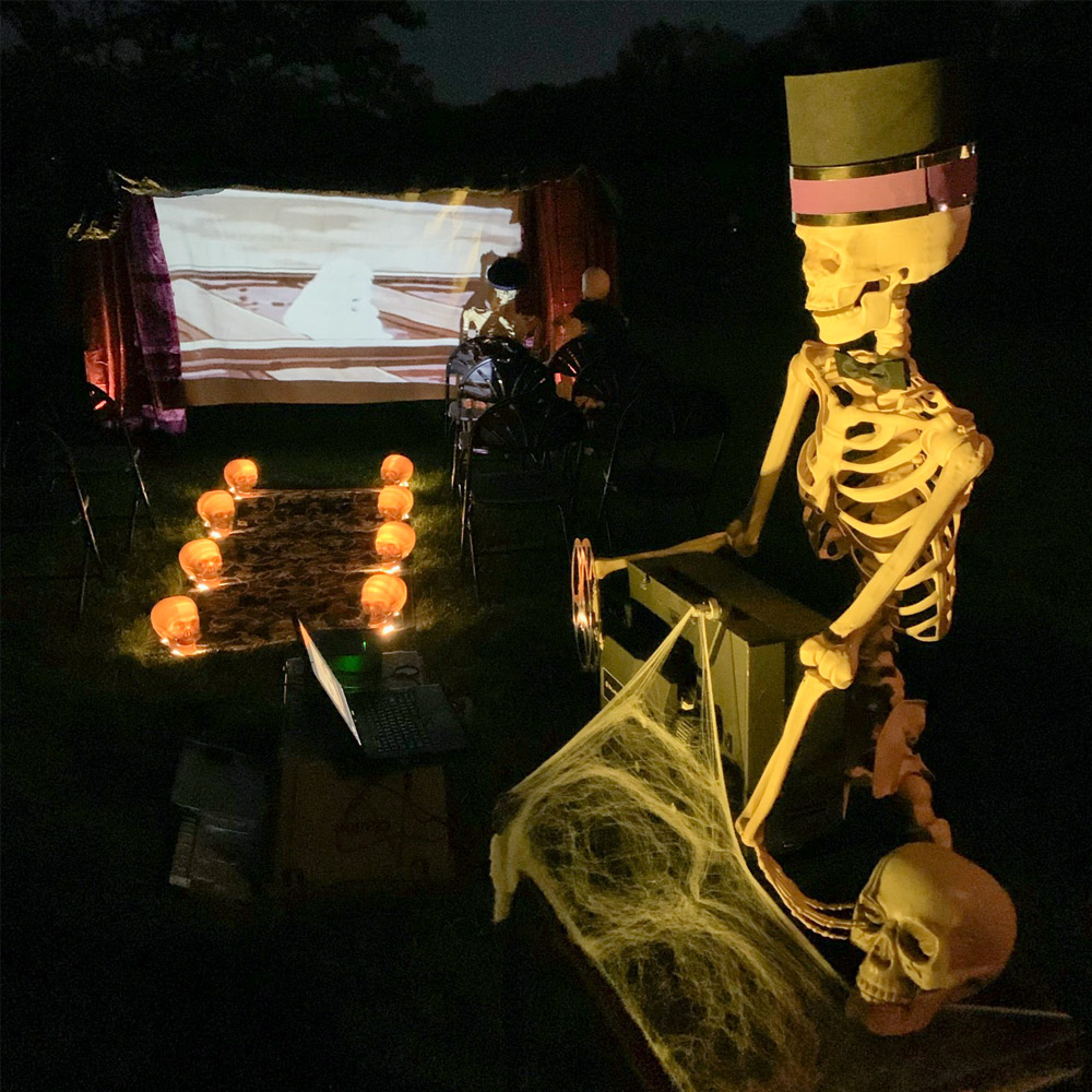 Night photo of Halloween theater with skeleton in front of projector.