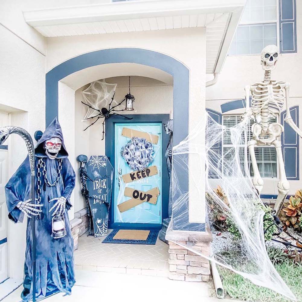 A blue and white front porch decorated for Halloween with a grim reaper. 
