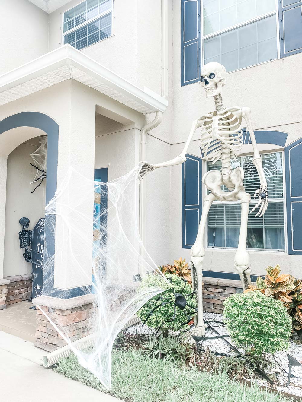 A giant skeleton with LED eyes standing in a front yard.