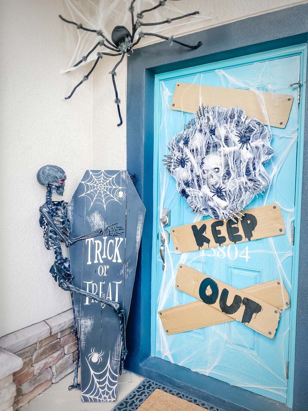 A front porch decorated for Halloween with skeletons, spiders, spider webs, and a keep out sign.