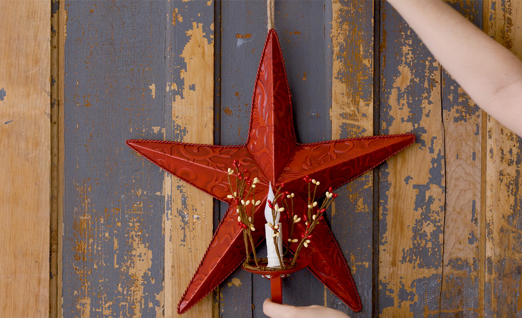 A red star with candle holder is hung on a front door.