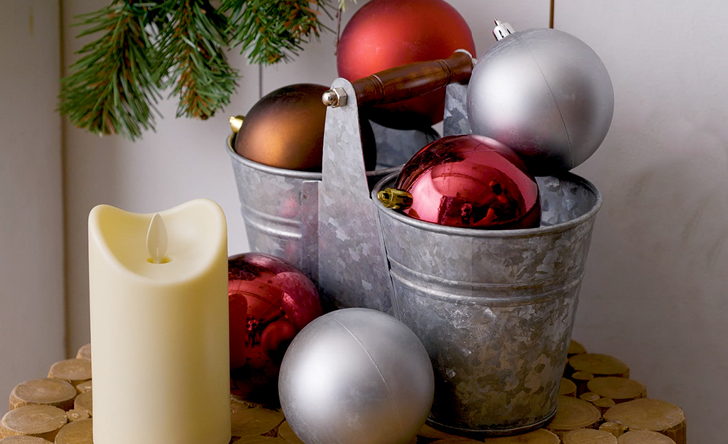 Ornaments in a decorative holder and a flameless candle sit atop a stool.