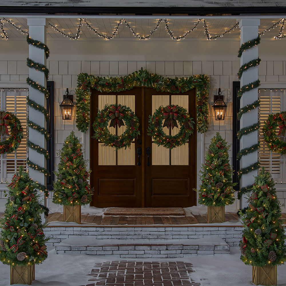 A doorway and porch decorated in Christmas lights.
