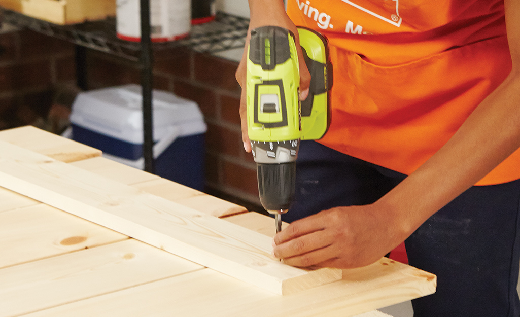 a person screwing pieces of plywood to each other a person screwing pieces of plywood to each other