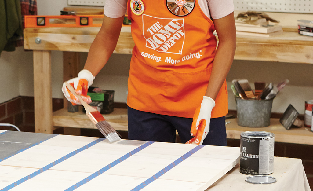 a person applying paint to a strip of plywood a person applying paint to a strip of plywood
