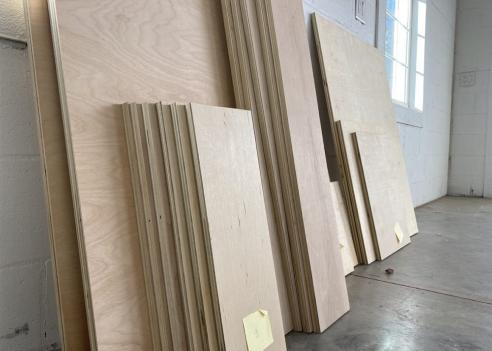 Three large stacks of plywood in various sizes