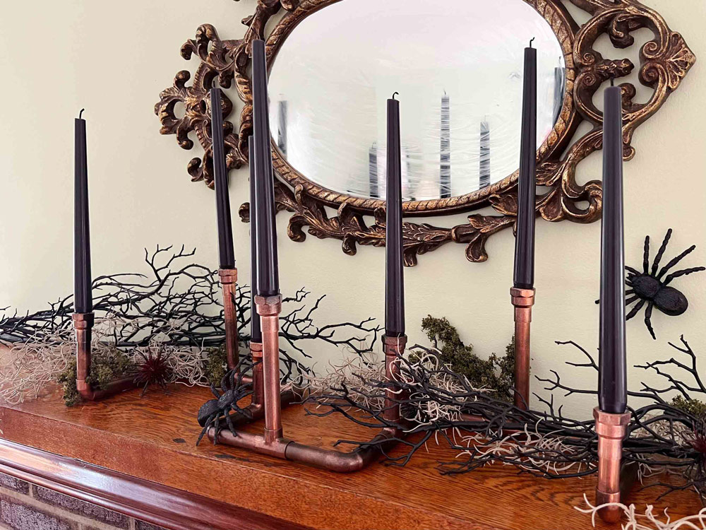 Creepy candles are displayed on a tabletop in front of a scary decorated mirror.