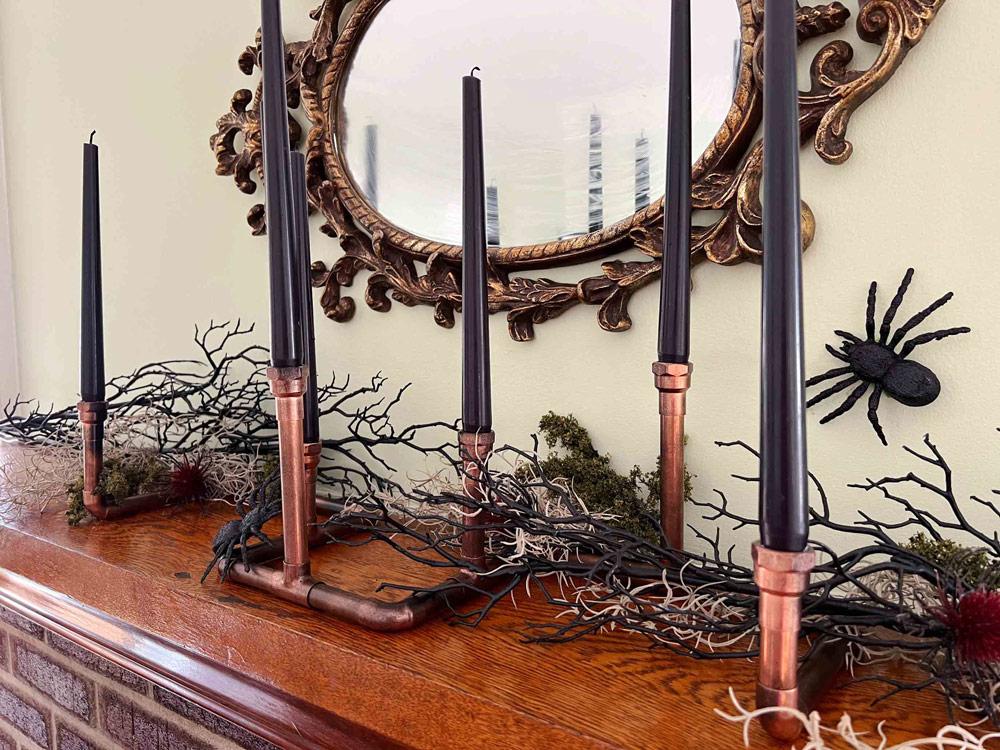 Creepy candles are displayed on a tabletop in front of a scary decorated mirror.