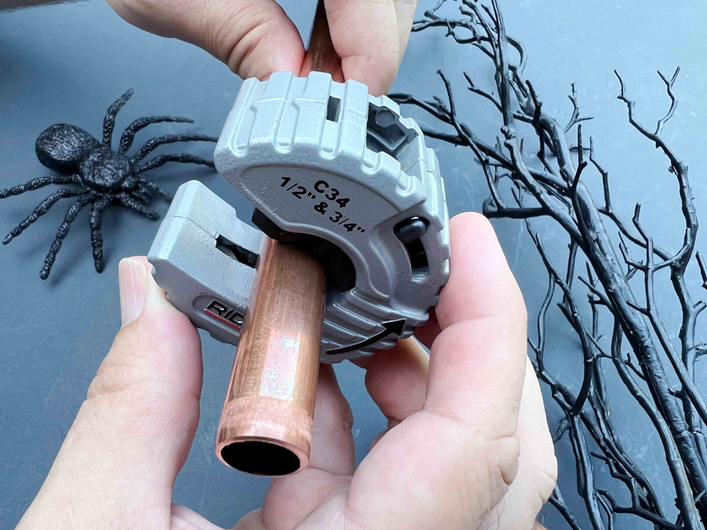 A hand holding a Ridgid copper pipe cutter. A hand holding a Ridgid copper pipe cutter.