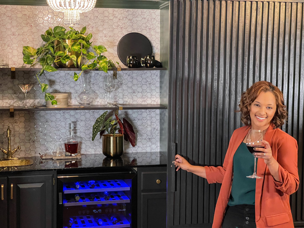 Women standing beside renovated wet bar space with a drinking glass in hand.