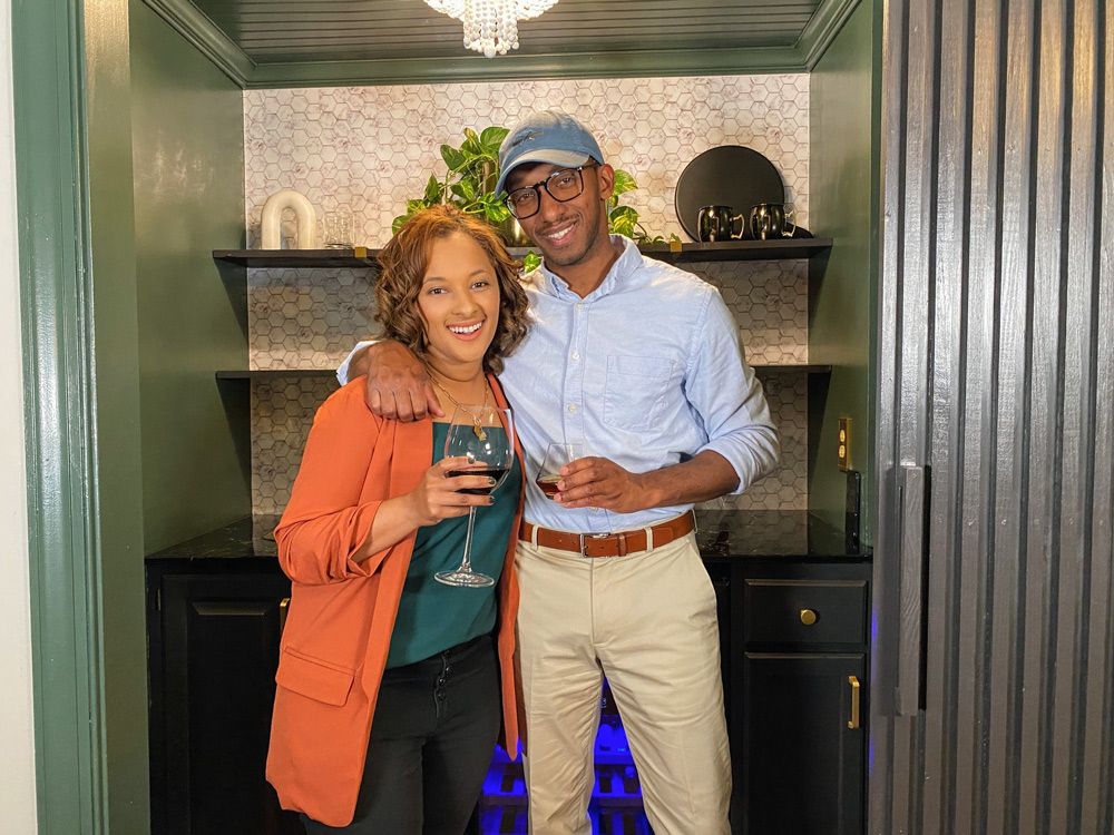 Woman and man standing in front of remodeled wet bar holding drinking glasses.