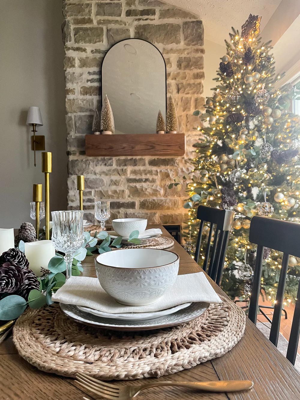 Dining room with dinnerware and Christmas tree in the background.