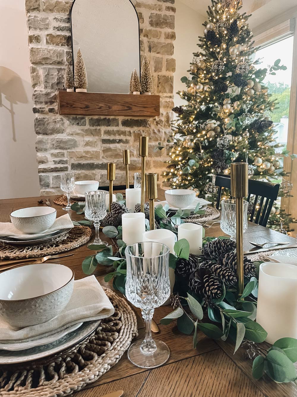 Dining room with dinnerware and Christmas tree in the background.