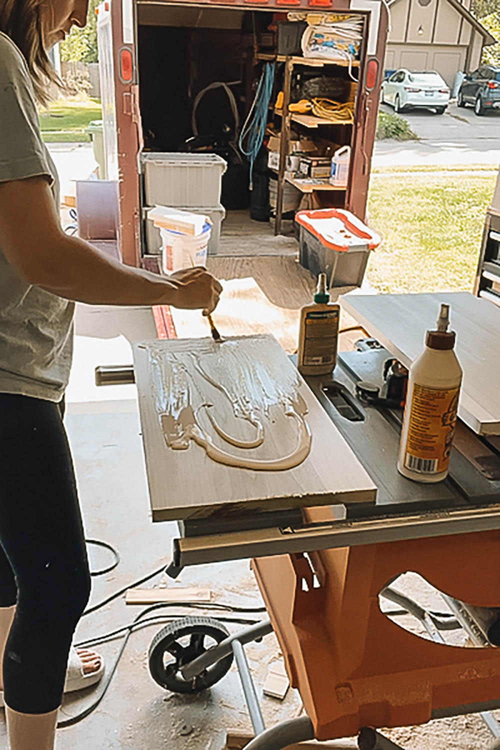 Woman spreading wood glue over one side of wooden board. Woman spreading wood glue over one side of wooden board.