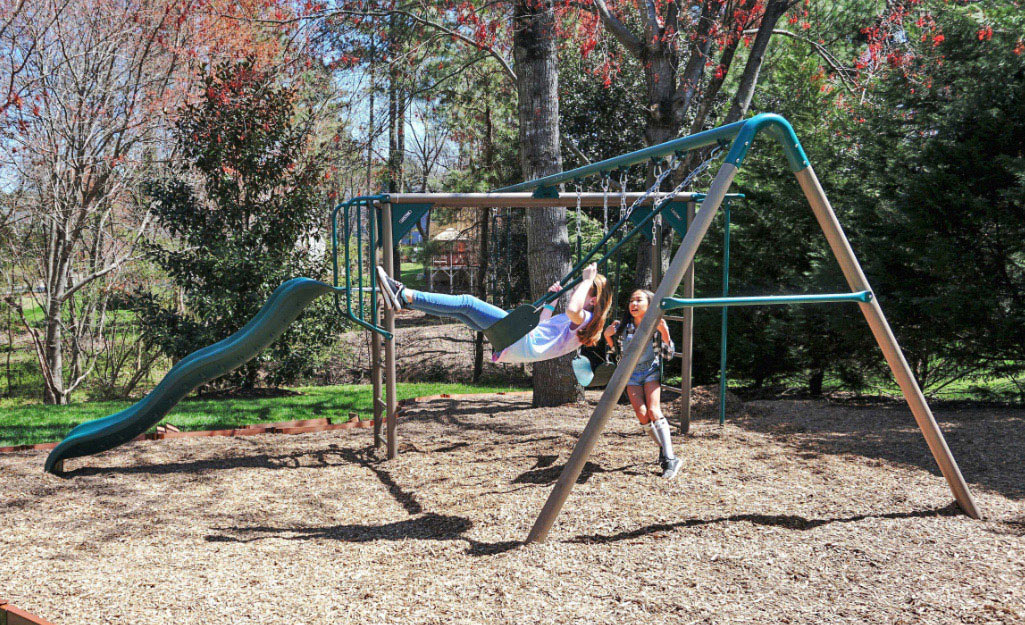 A swing set with wood mulch.