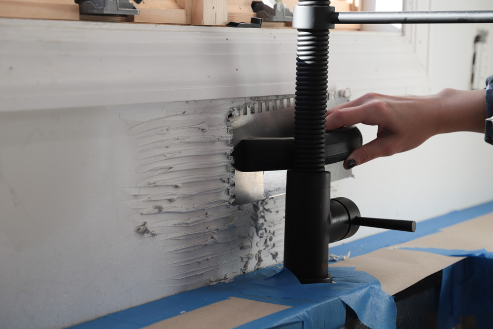 A person using a trowel to apply tile adhesive.