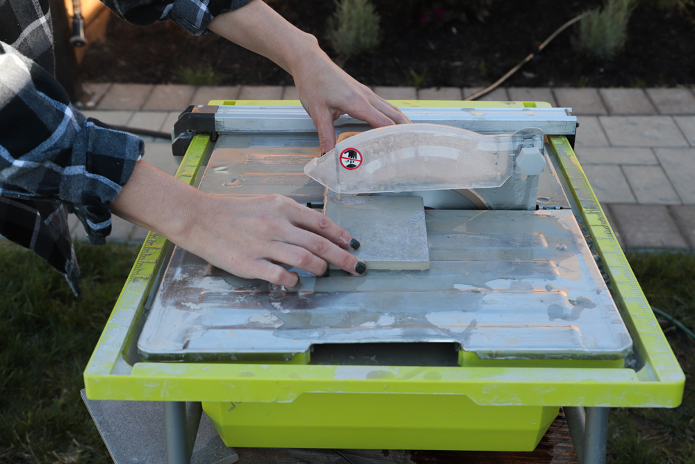 A person using a tile cutter to create specific shapes for the tile.
