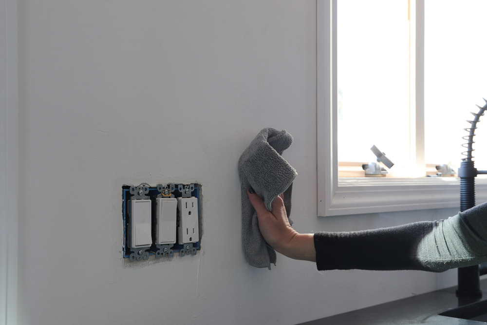 A person using a cloth to wipe down the wall.