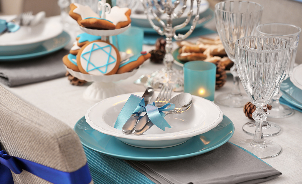 A table set with Hanukkah cookies and a chair with a blue ribbon around it.