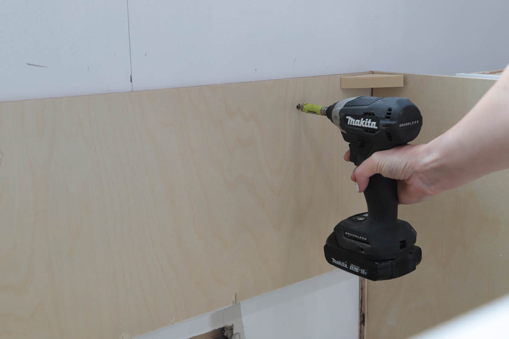 Person using a Makita drill to insert nails into a wood panel.