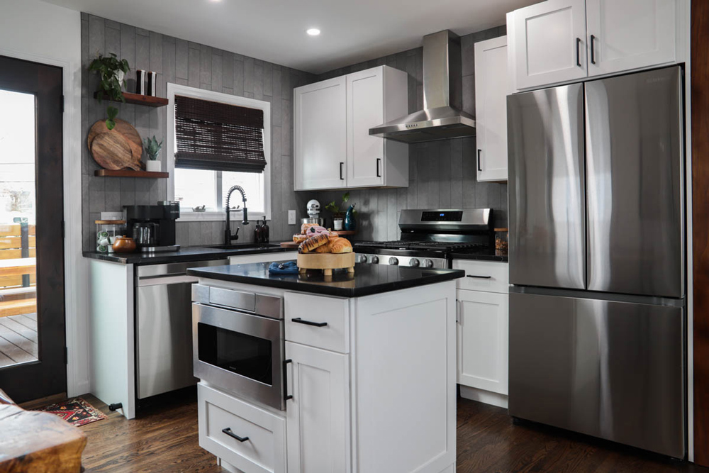 Small kitchen with an island, black marble countertops, white cabinets, and stainless steel appliances.