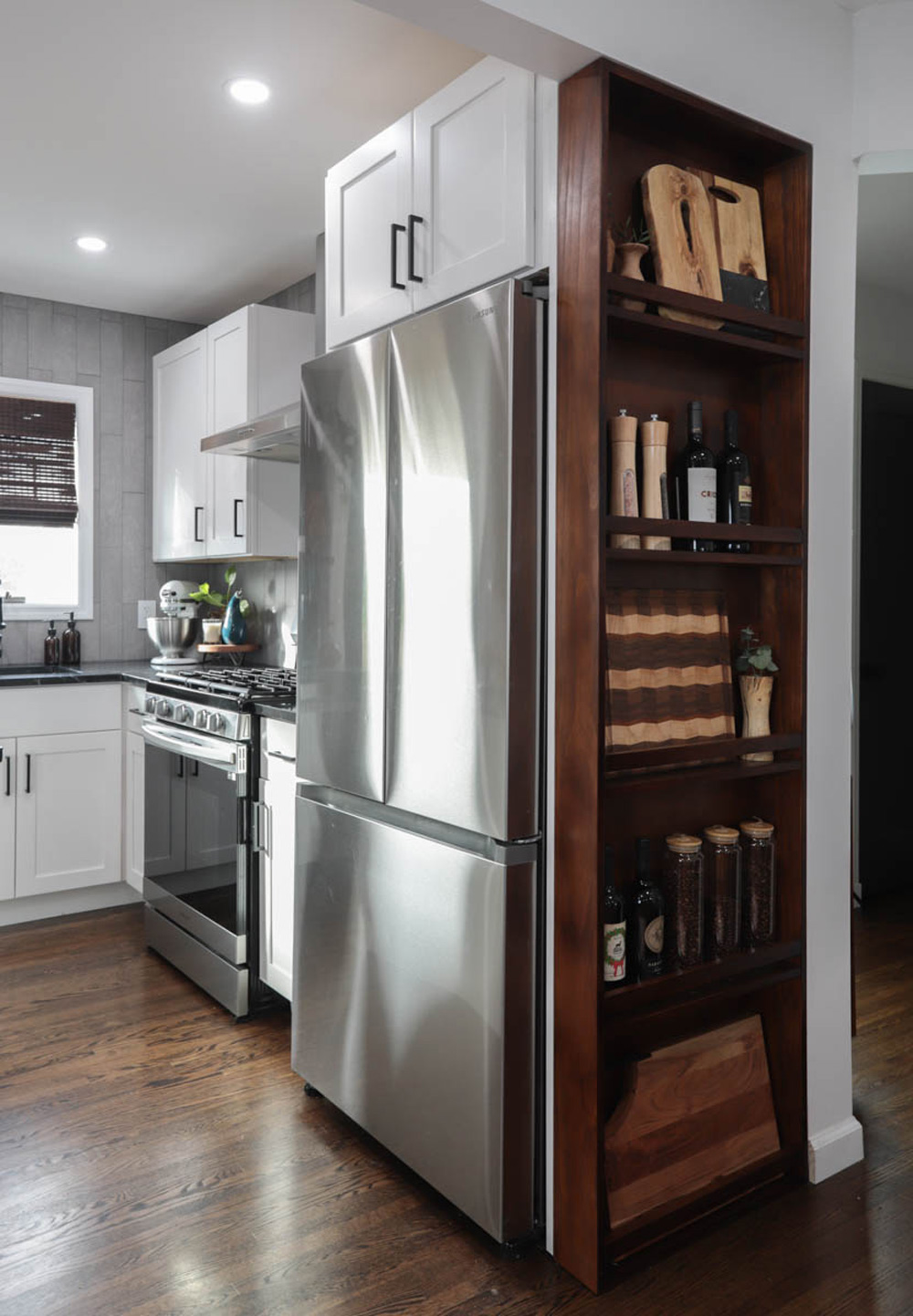 Refrigerator with a stocked, wooden shelved rack on the side.