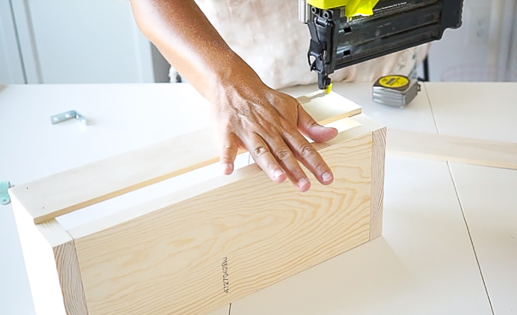 Person uses a power tool on the wood pieces.