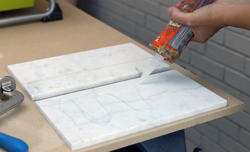 A person applying adhesive to the backs of tile pieces.