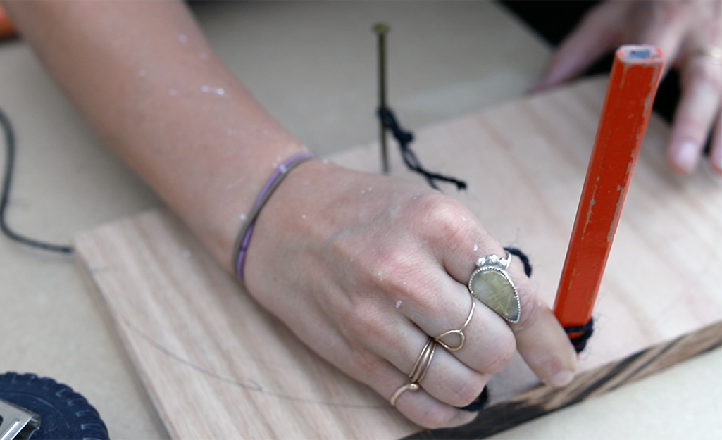 A person marking a curve on wood.