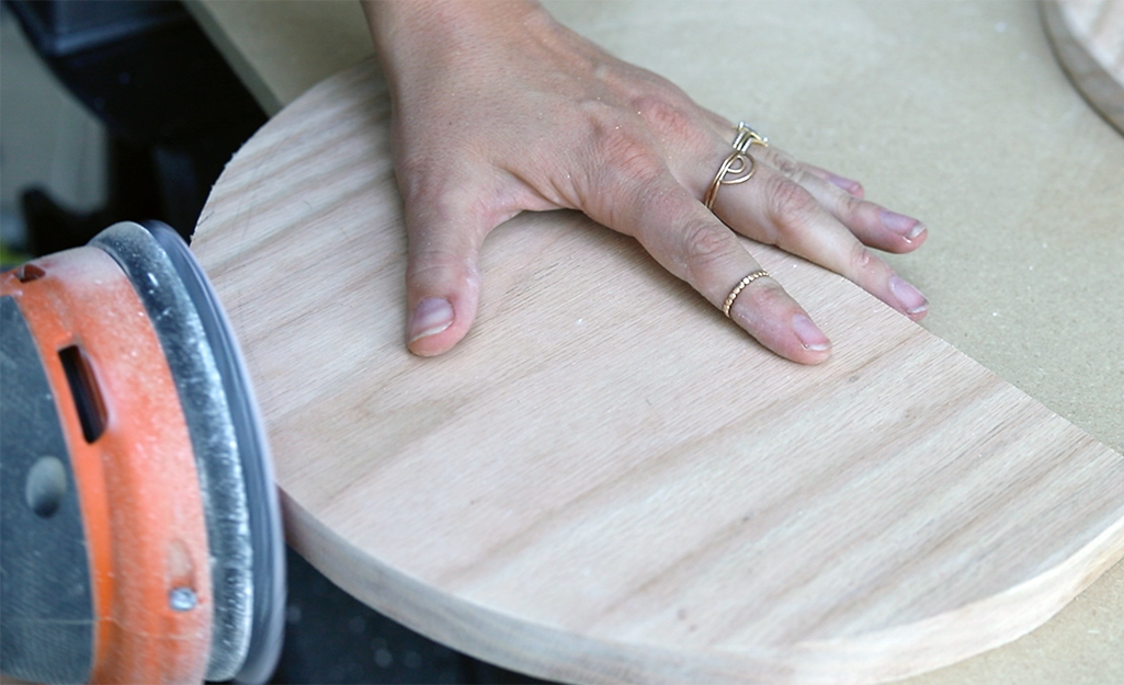 A person sanding wood with a power sander.