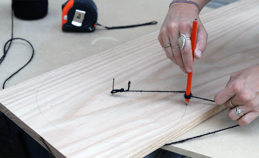 A person marking a circle on a wood board.