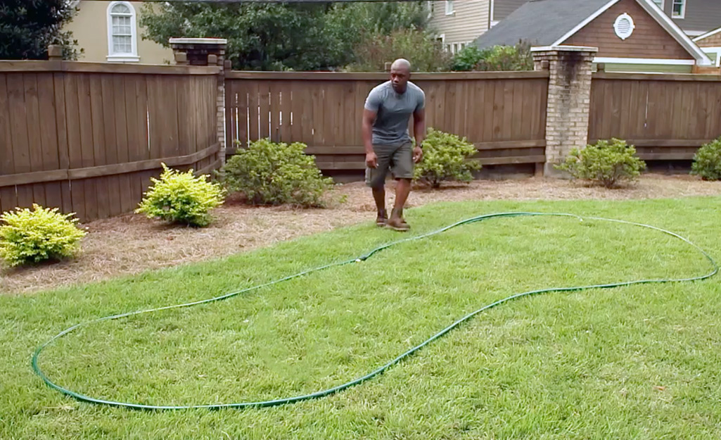 A person outlining a DIY putting green with tubing.