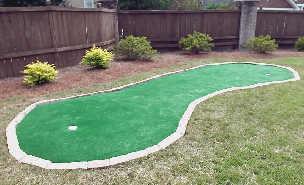 A finished DIY backyard putting green with a single cup.