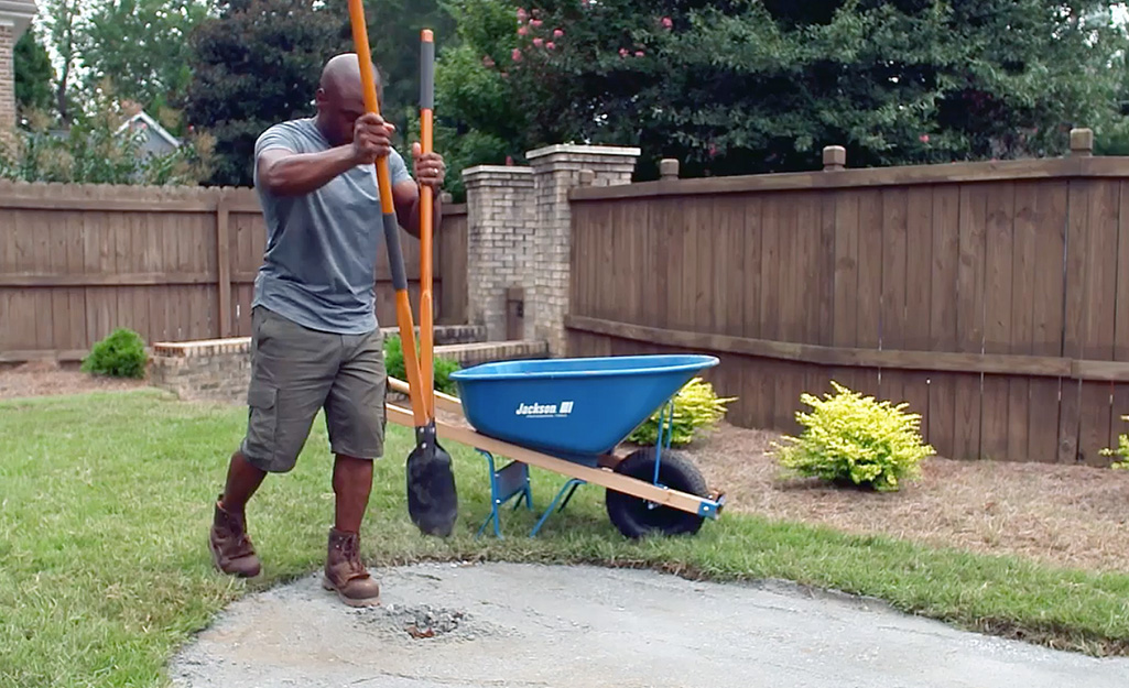 A person digging holes for a golf cup in a backyard putting green.