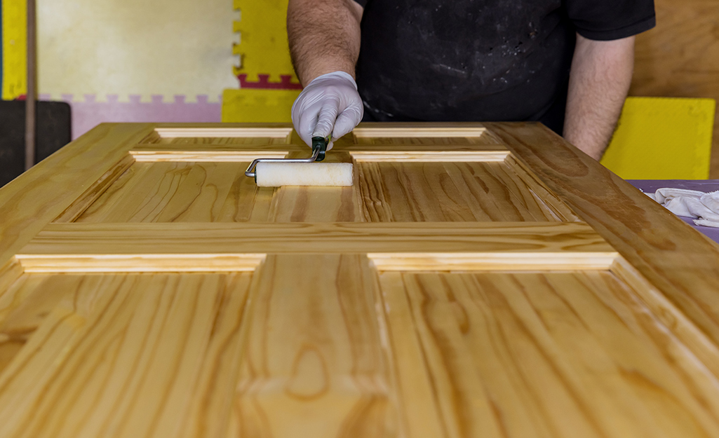 A person applies a coat of stain to a barn door.