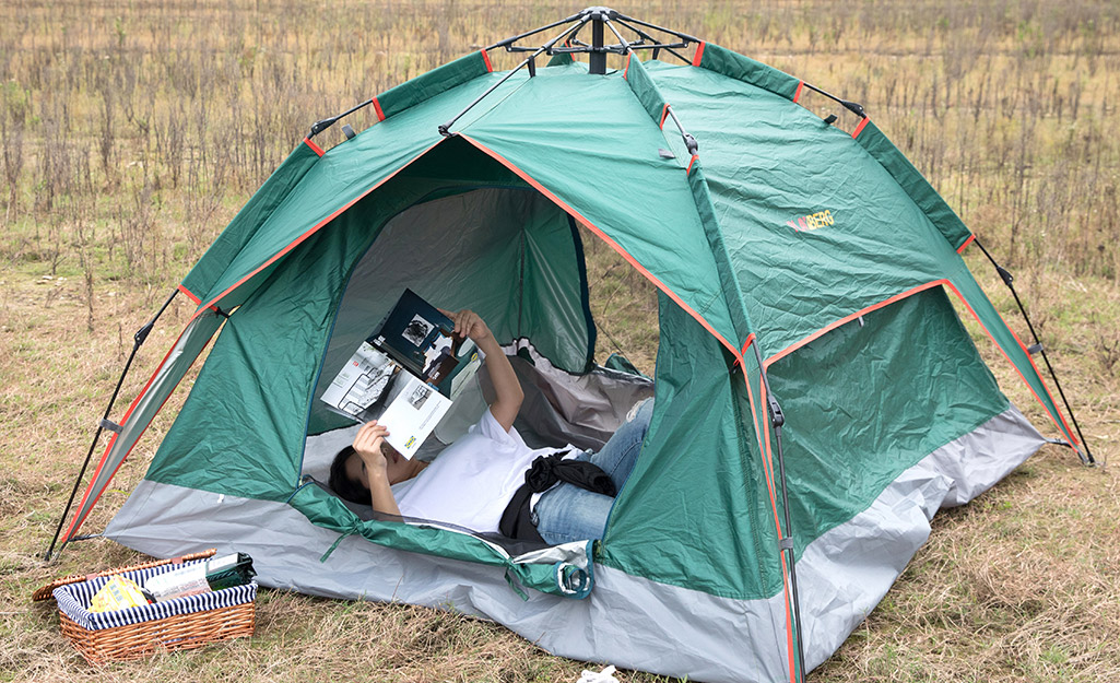 A person reading in a pop-up camping tent.