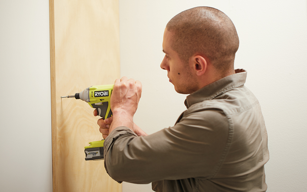 Man adding a board to the closet wall. Man adding a board to the closet wall.
