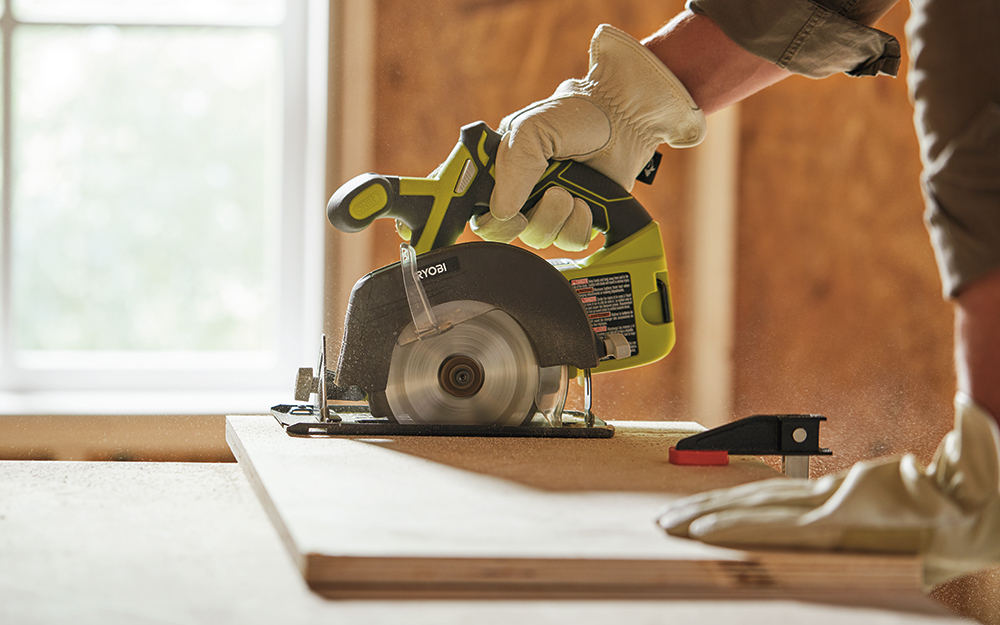 Man using a circular saw to cut a shelf for the closet organizer. Man using a circular saw to cut a shelf for the closet organizer.