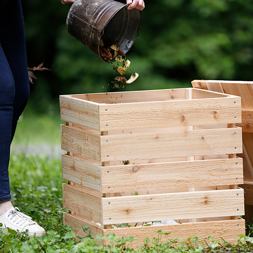 Woman emptying food scraps into a DIY compost bin.