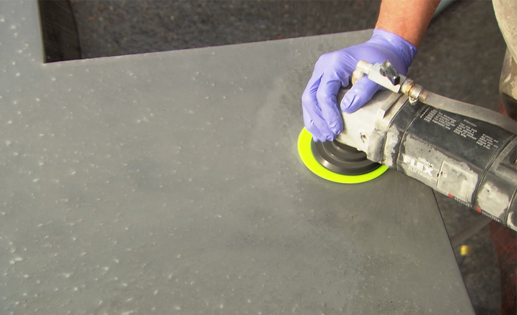A person polishing a concrete countertop with a grinder.