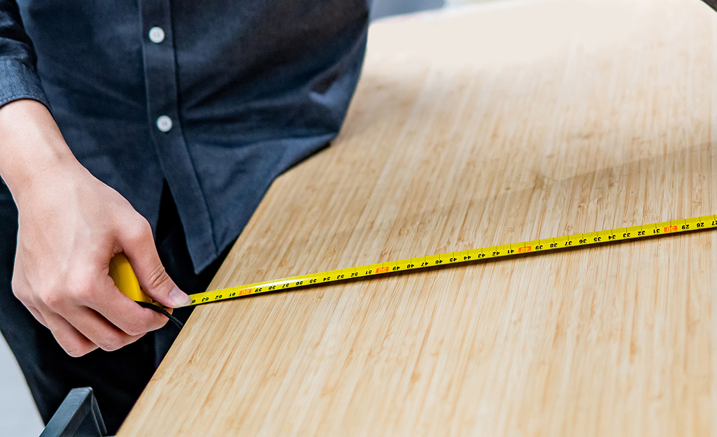 A person measuring a project panel with a steel tape measure.