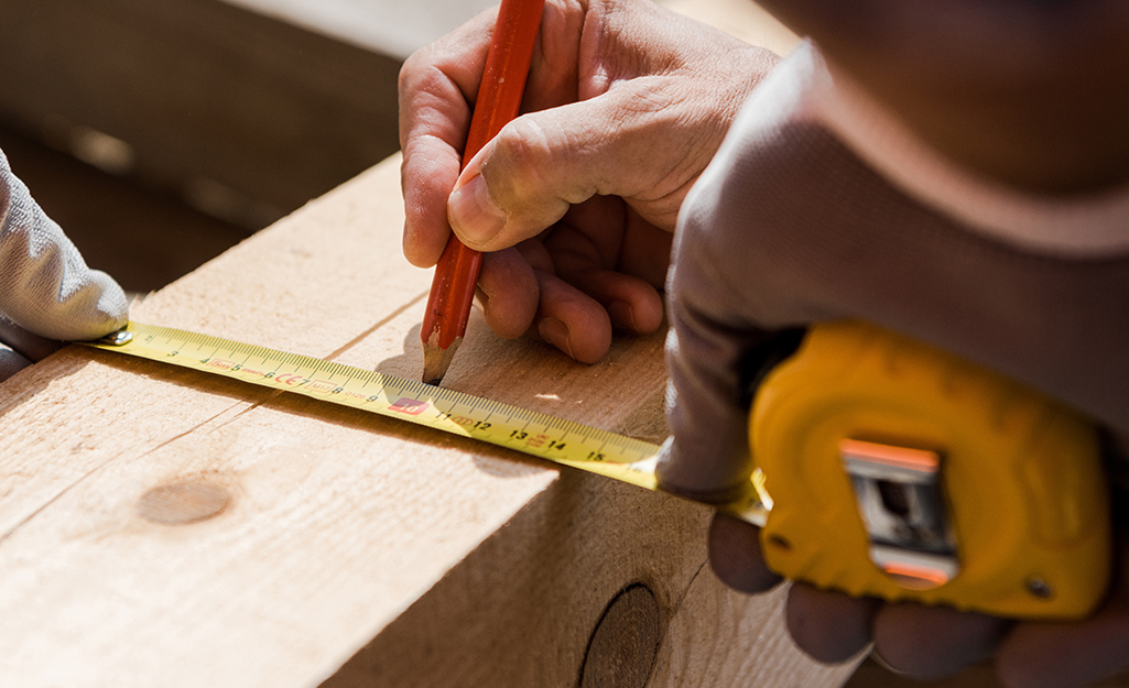A person marking an angle on a wood board. A person marking an angle on a wood board.