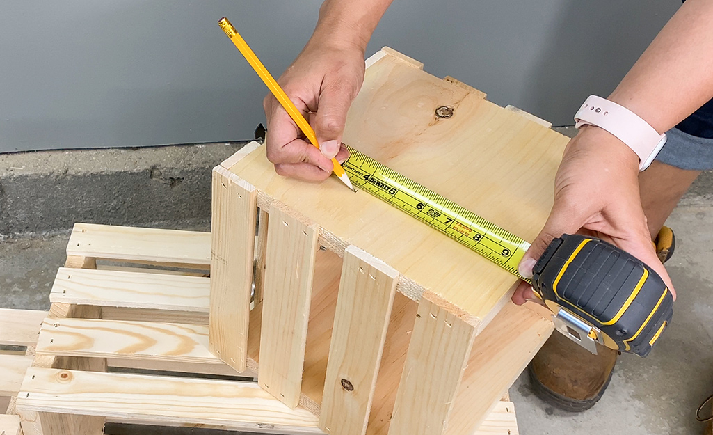 Person measuring and marking the side of a crate.