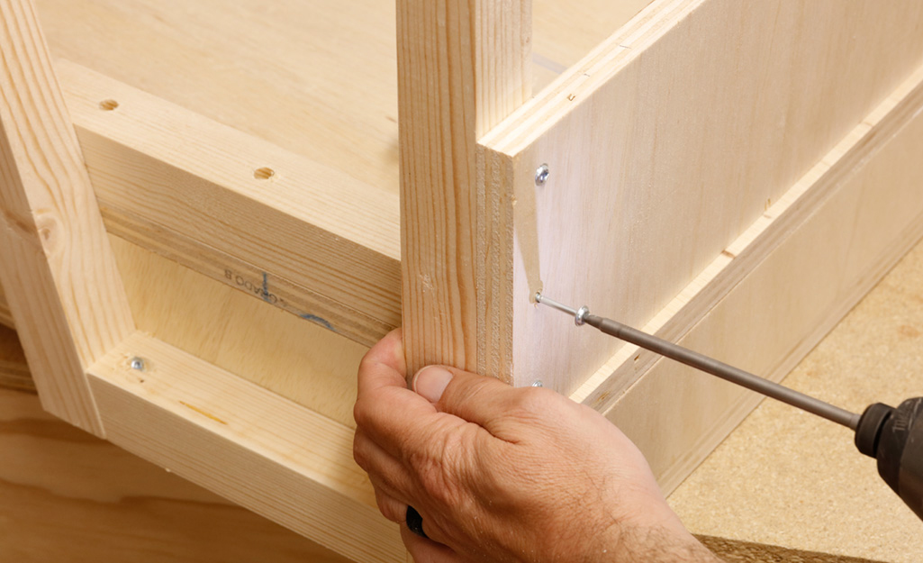 A screwdriver is used to turn on the screws that connects the plywood pieces of a DIY desk. A screwdriver is used to turn on the screws that connects the plywood pieces of a DIY desk.