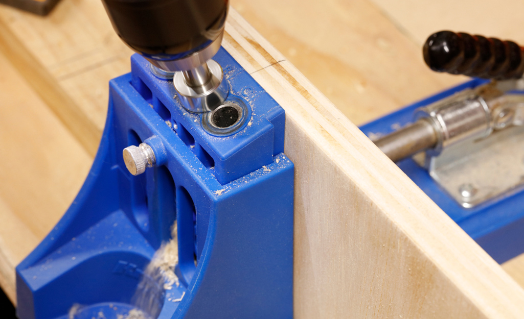 A drill is used to make pocket holes in plywood for a DIY desk project. A drill is used to make pocket holes in plywood for a DIY desk project.