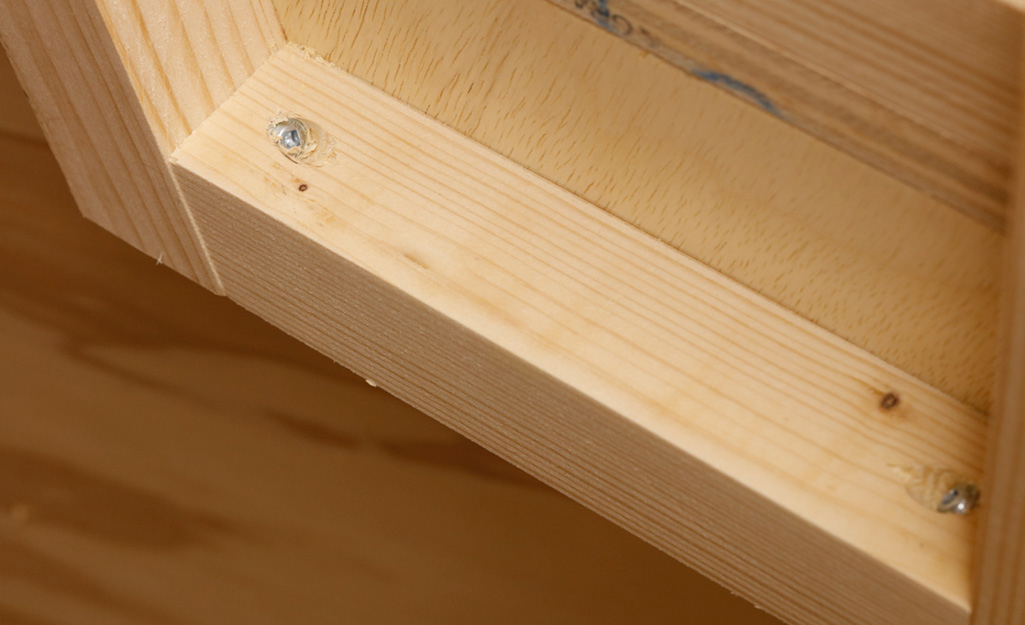 Screws are used to attach a piece of plywood that serves as rear support to a DIY desk Screws are used to attach a piece of plywood that serves as rear support to a DIY desk
